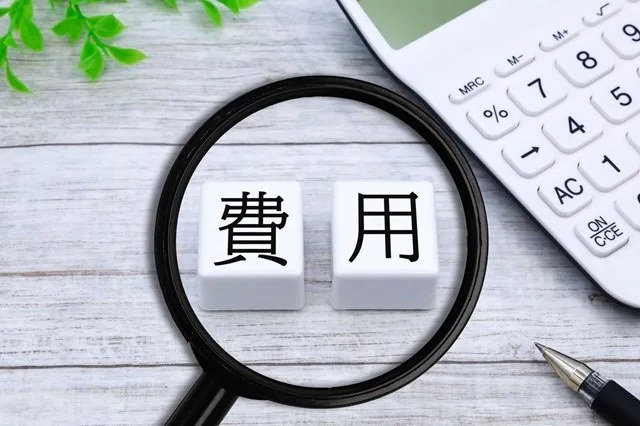コスト高騰の経営課題を表す電卓と虫眼鏡のイメージ